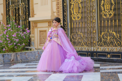 A person wearing a Rapunzel-themed lilac-colored net dress with long sleeves and a flowing design, standing in front of an ornate door.